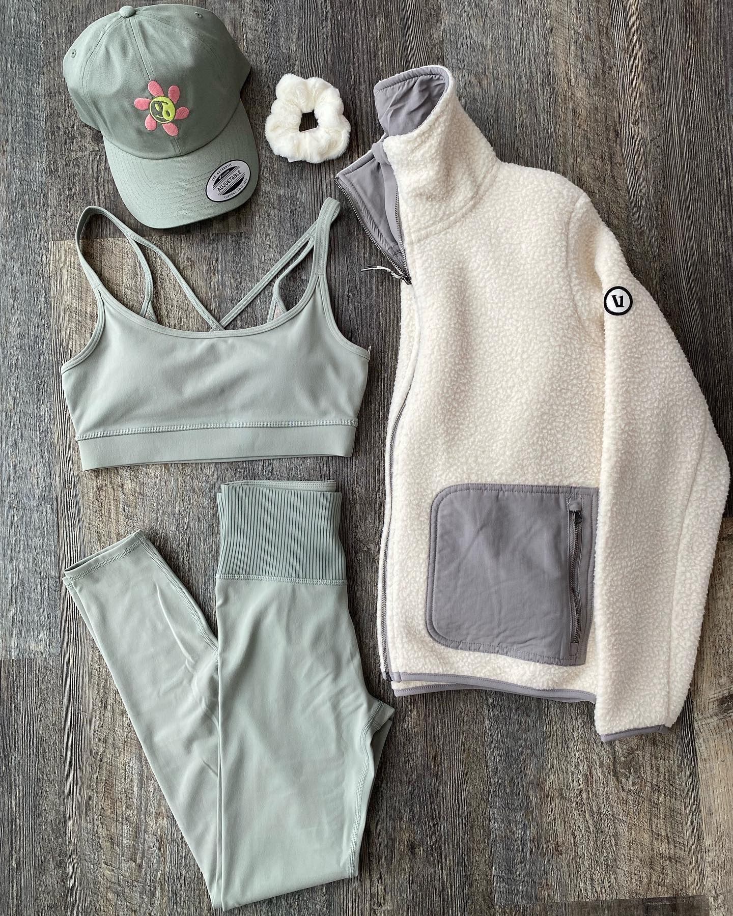 Children’s clothing set on wood: cap, sports bra, leggings, and fleece jacket with pockets.
