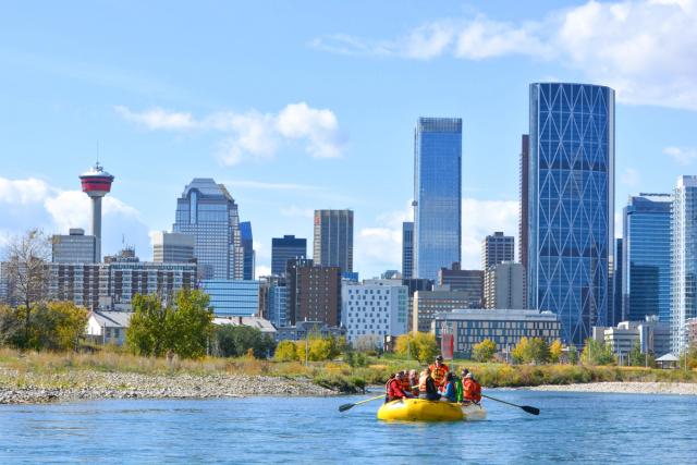 Tour group floating down the Bow River with downtown Calgary in the background.