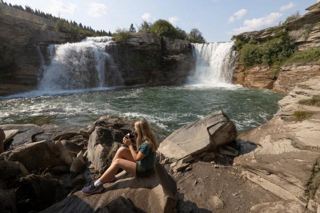 A woman looking out at the waterfall at Lundbreck Falls Campground.