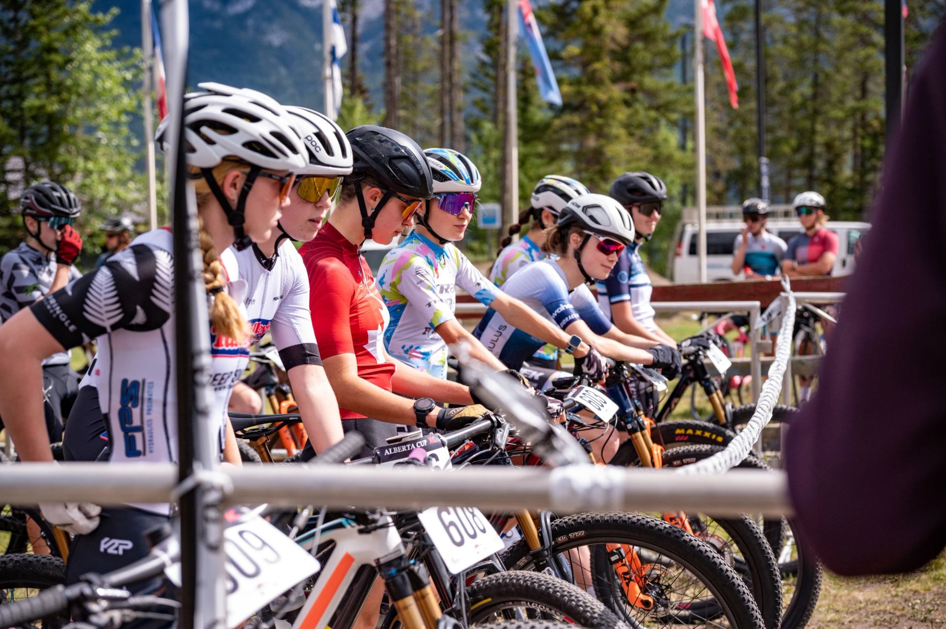 Mountain bike racers lined up behind the start barrier with helmets on and bikes ready at the Canmore Continental Series.