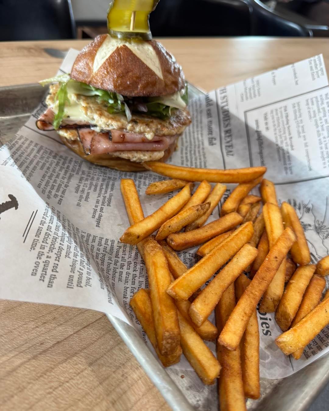 Loaded sandwich with fries presented on parchment paper at McLeod River Brewing Company.