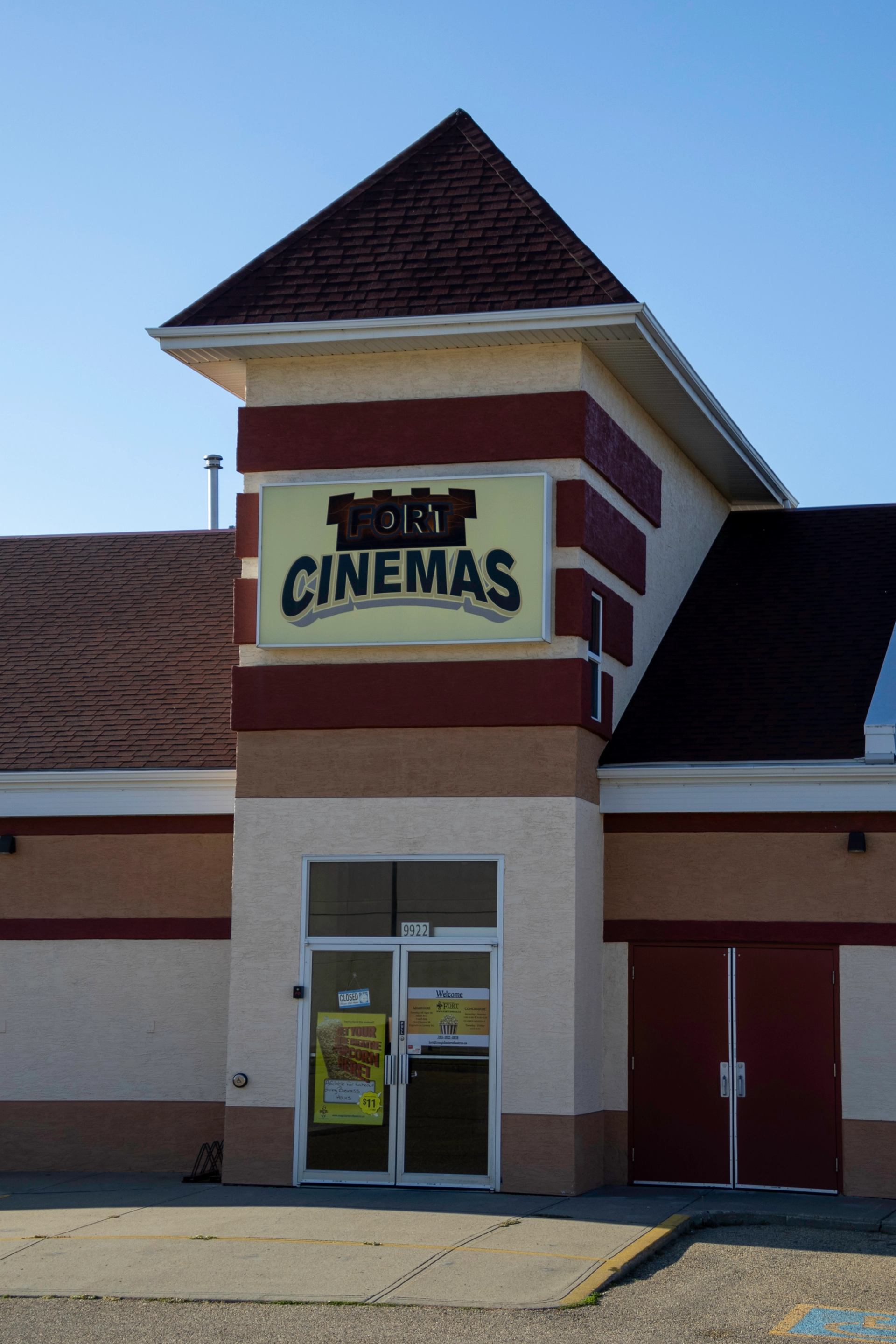 Movie theater with pointed roof and “CINEMAS” sign on red and beige brick facade.