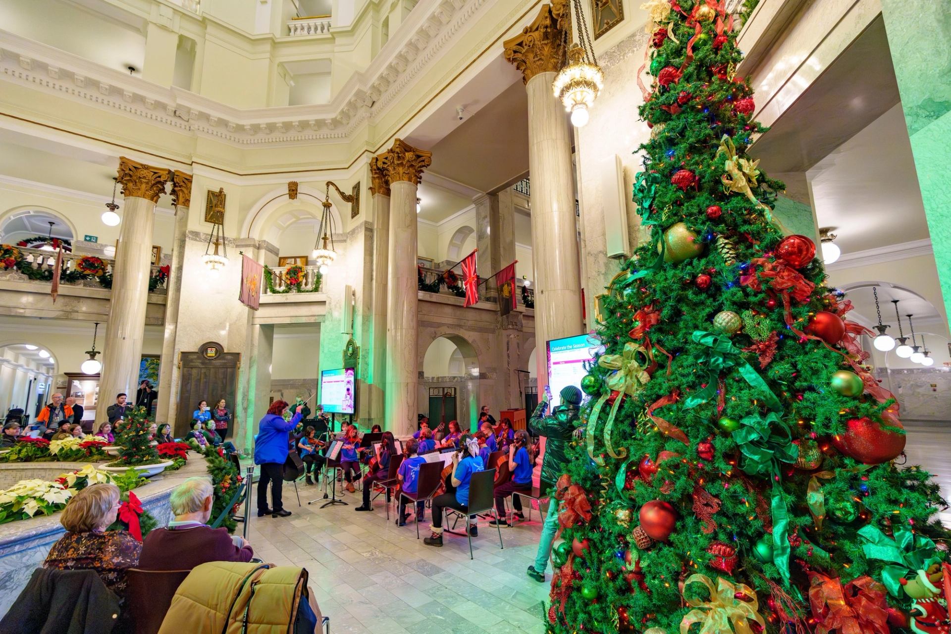 Decorated Christmas tree and musicians performing inside the Alberta Legislature.