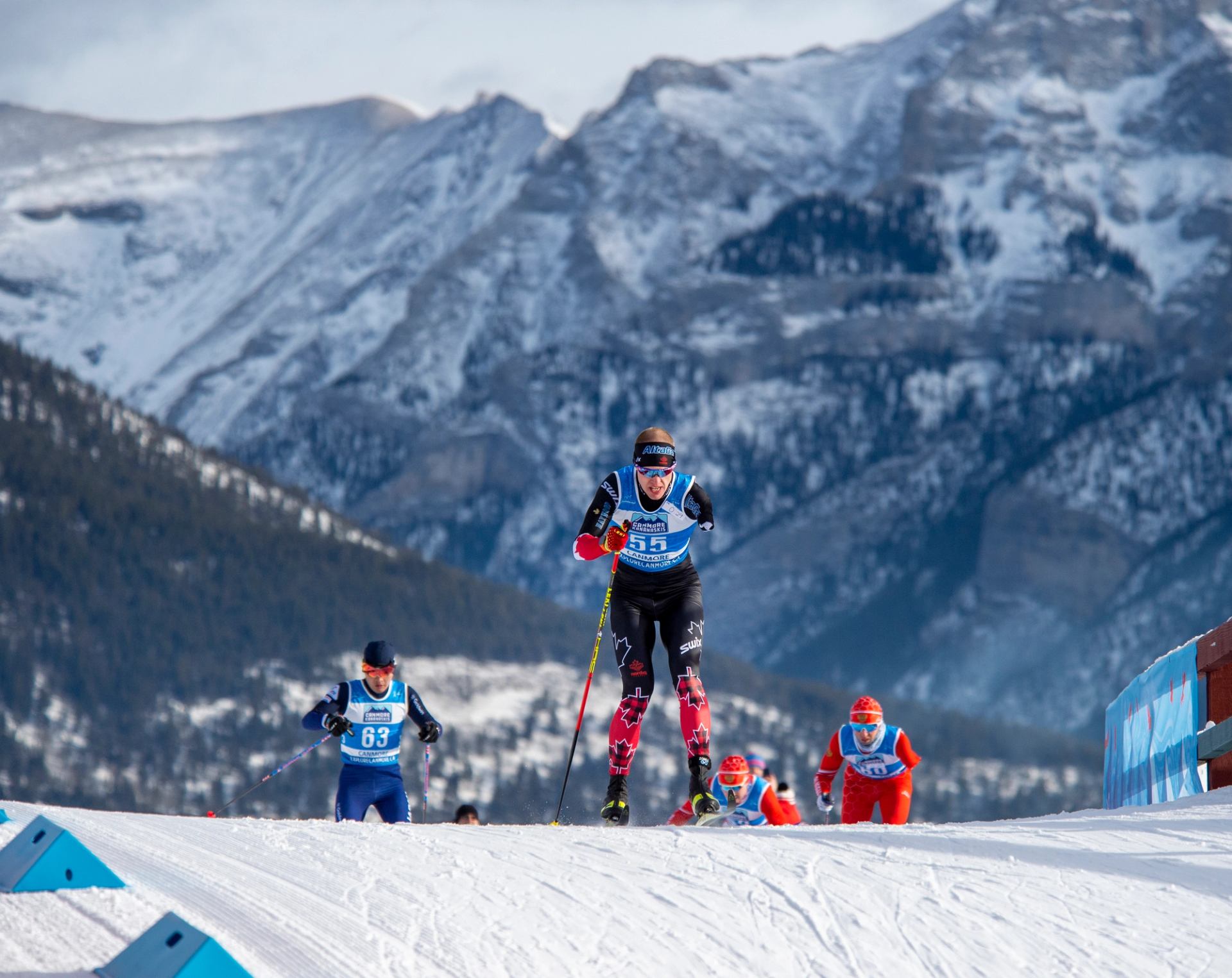  Para biathletes racing on snowy mountain with scenic peaks in the background.