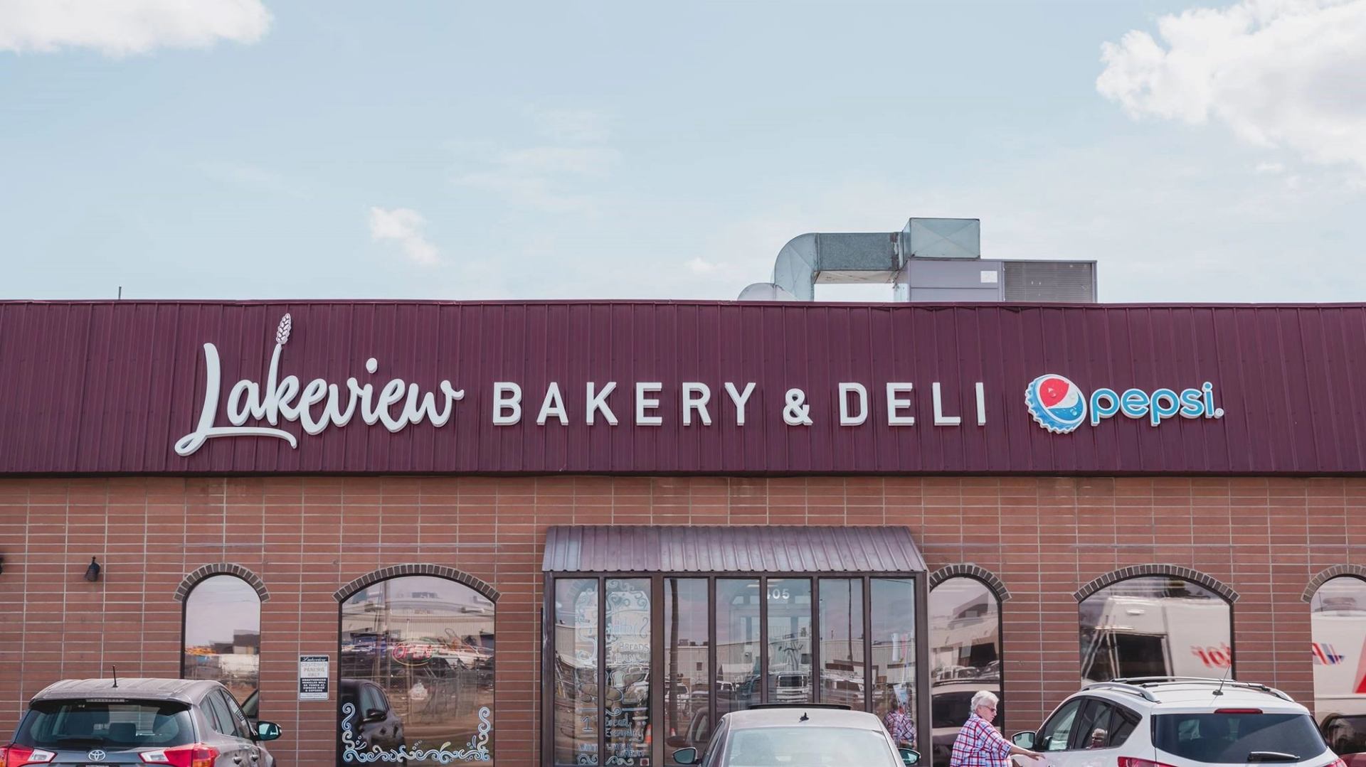 Exterior view of Lakeview Bakery & Deli storefront with signage and parked cars.
