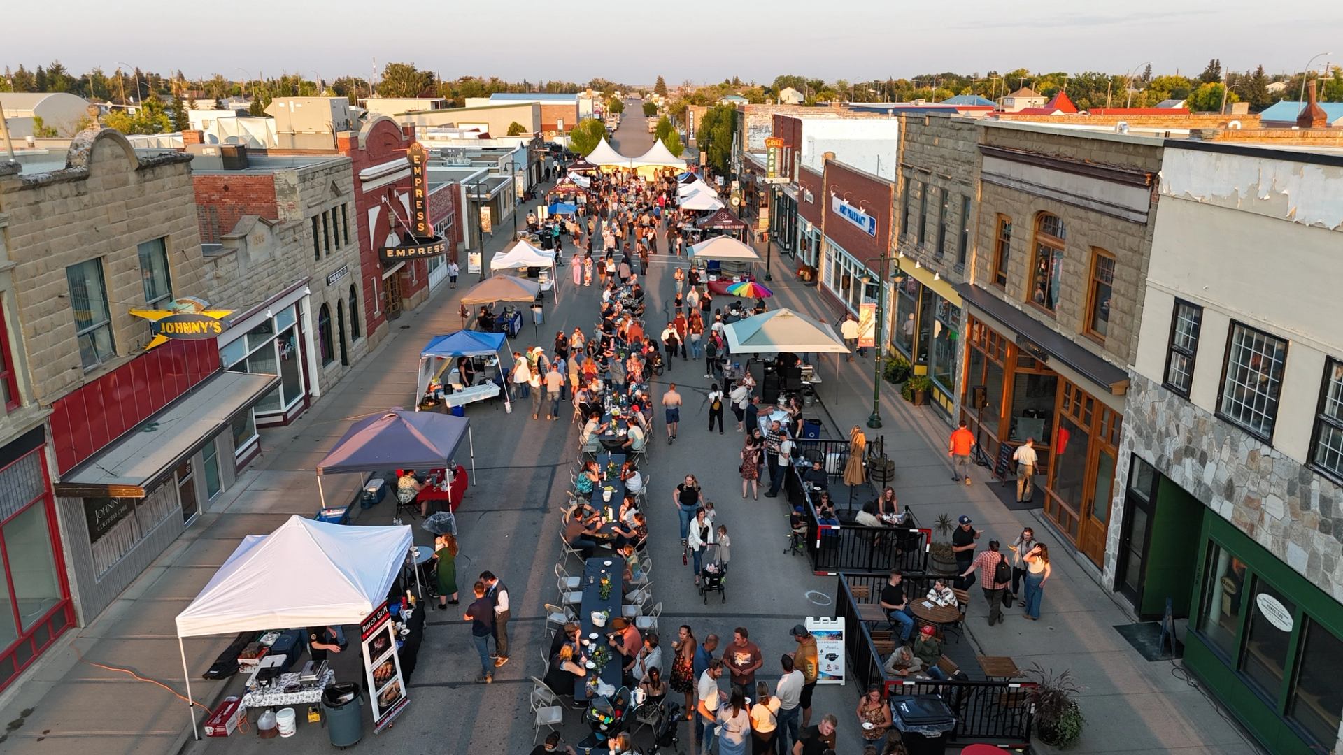 Aerial view of downtown street festival with vendor tents, long tables and crowds.