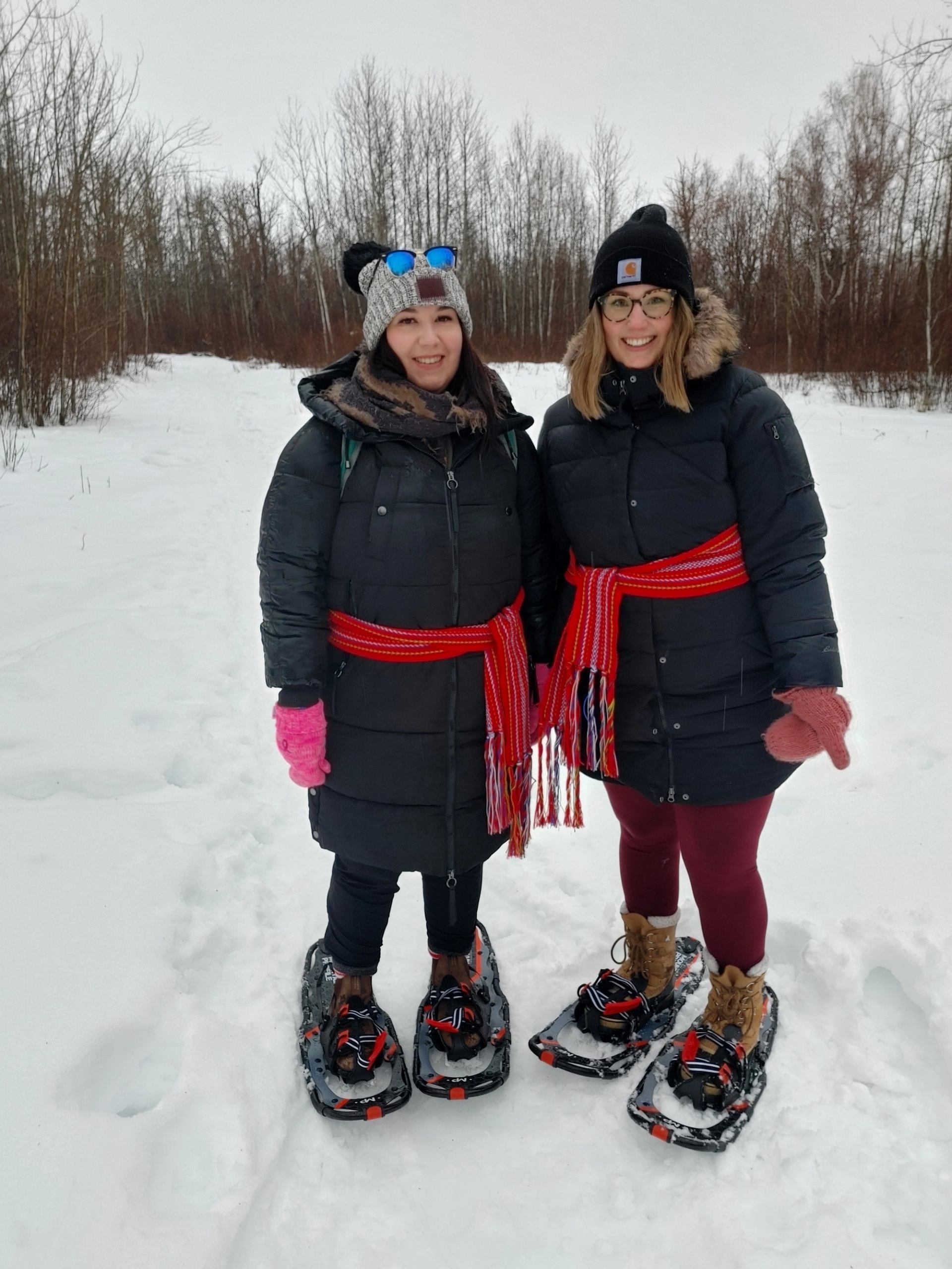Two women snowshoeing along a trail.