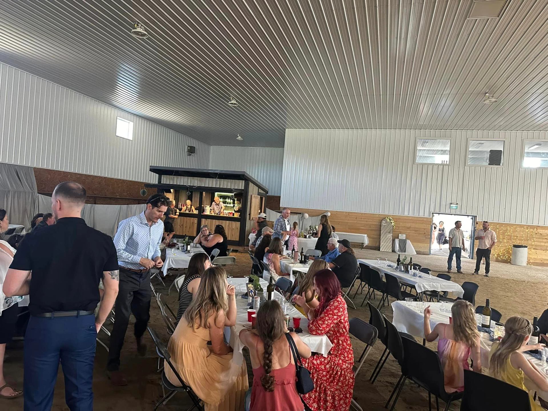 Guests gather around banquet tables inside a large metal-walled hall.