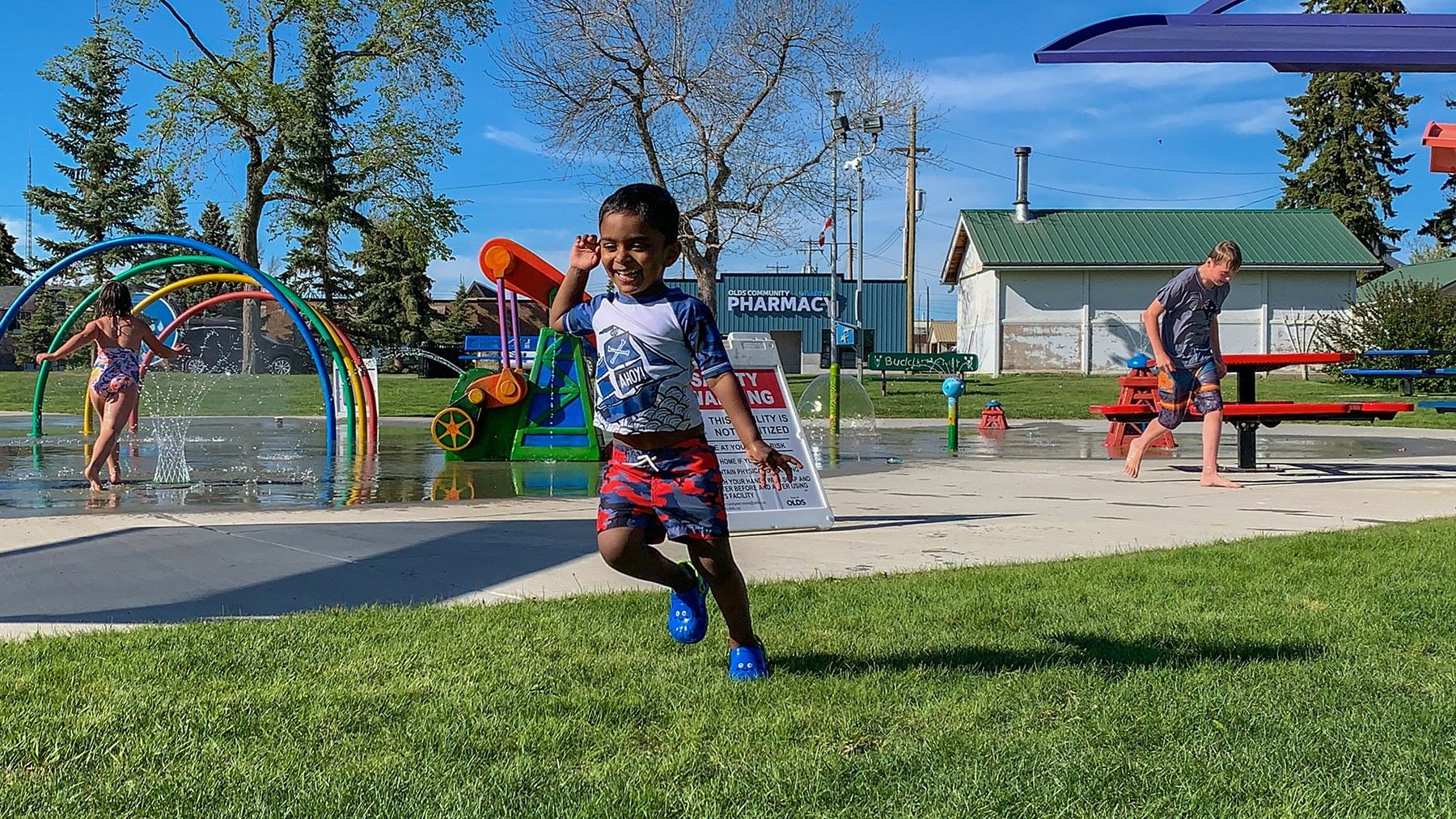 Kids and families enjoying water play and picnic time at Olds Splashpark.