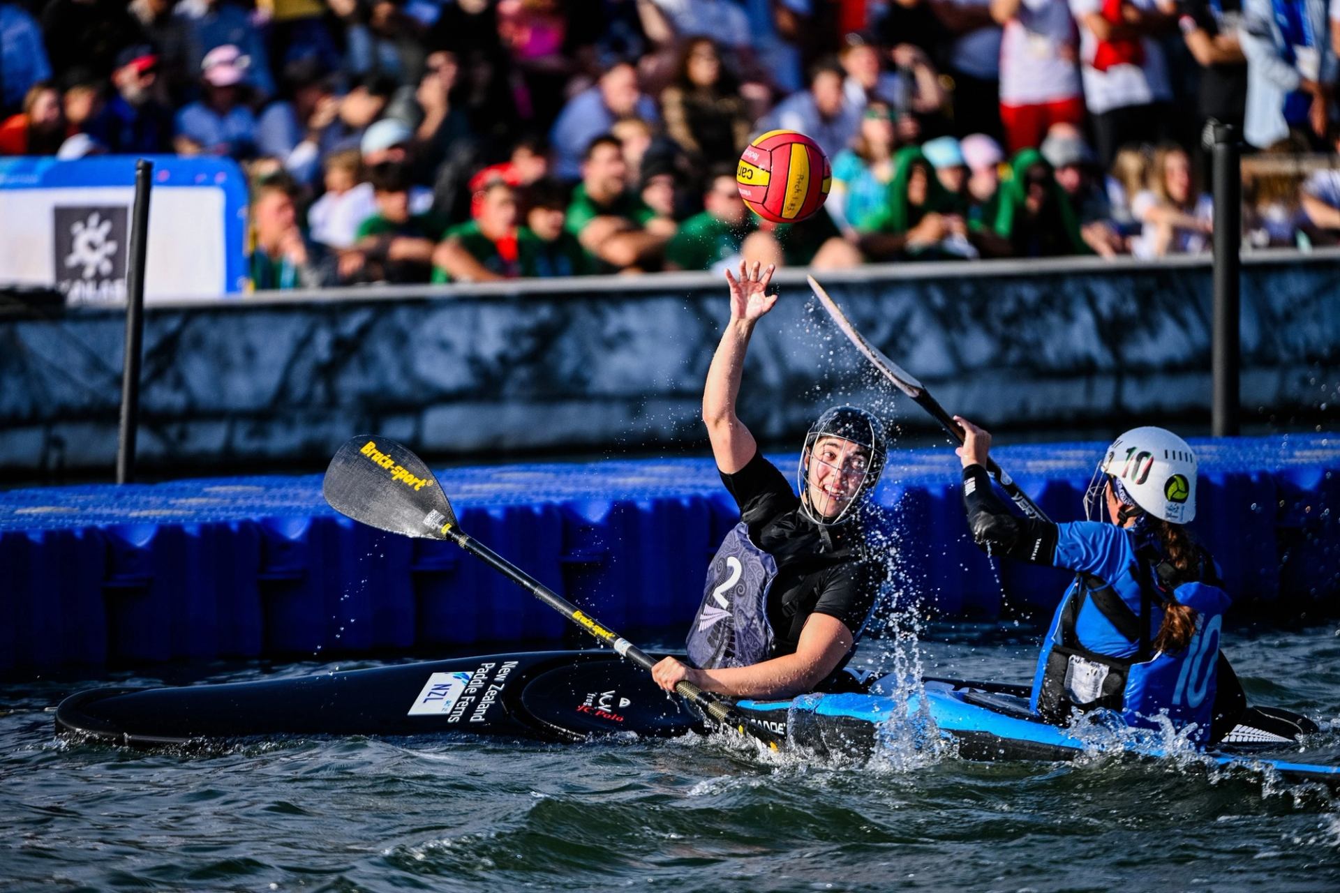 Two canoe polo players compete in the water.