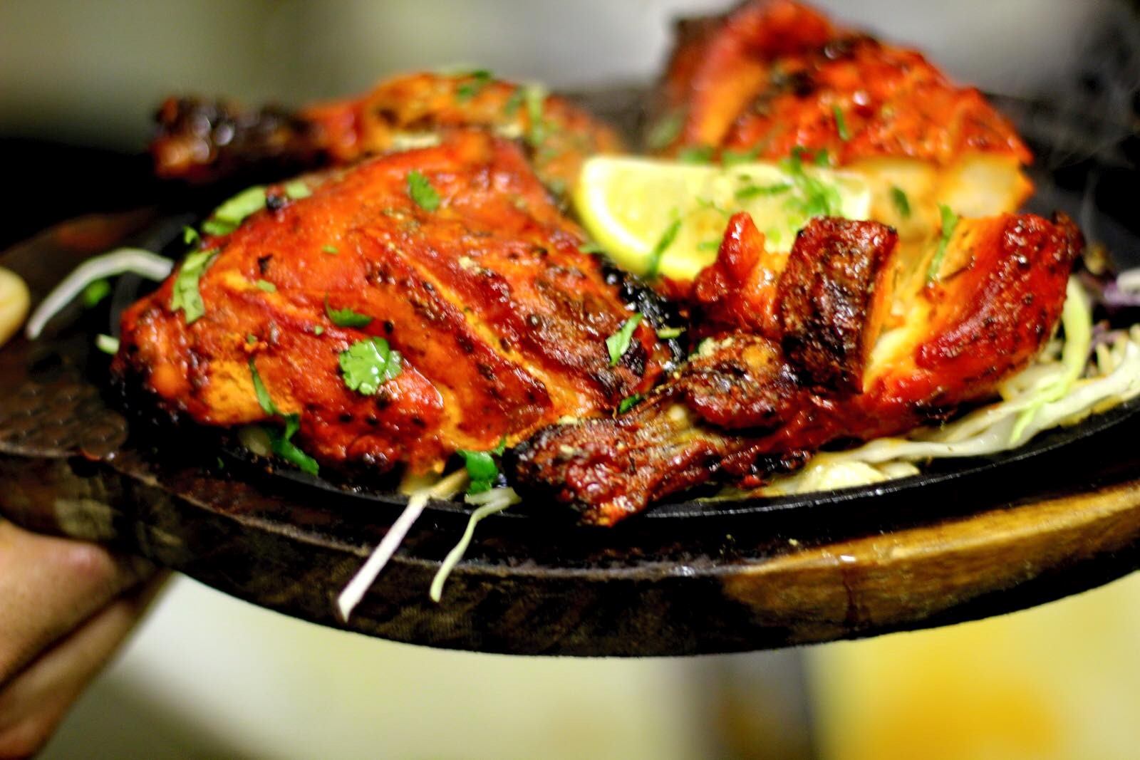 Grilled chicken platter with herbs and lemon wedges at Tandoor n Flame.