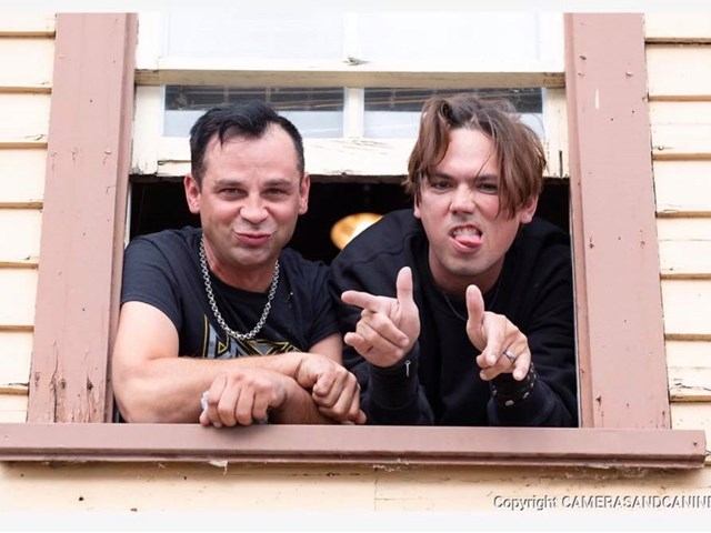 Man and another man in front window making peace signs at music event, Waynestock.