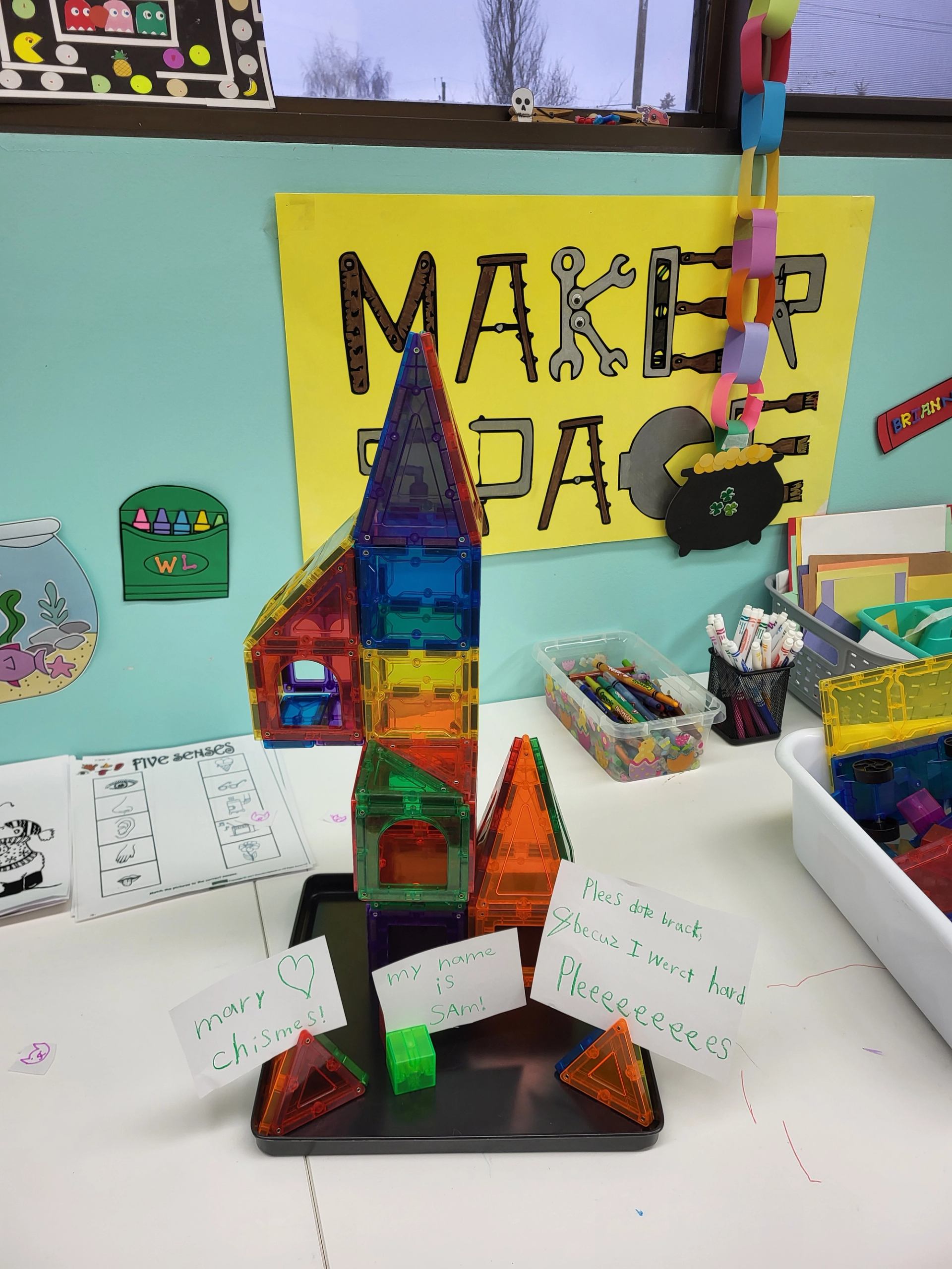 Colourful magnetic tile tower on classroom table with handwritten student notes around it.