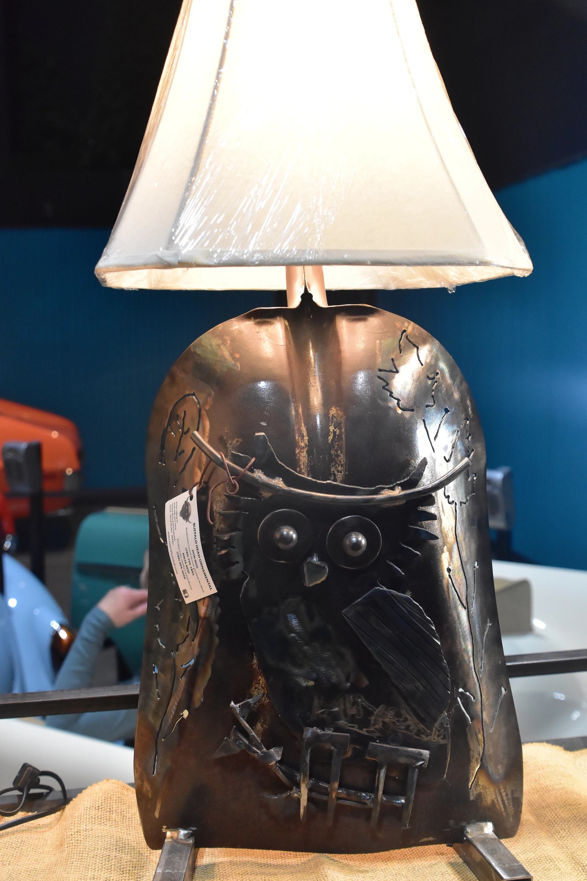 Metal lamp base featuring an owl design beneath a white lampshade.