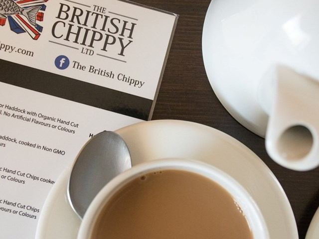 The British Chippy business card beside menu, tea cup, spoon and cream jug.