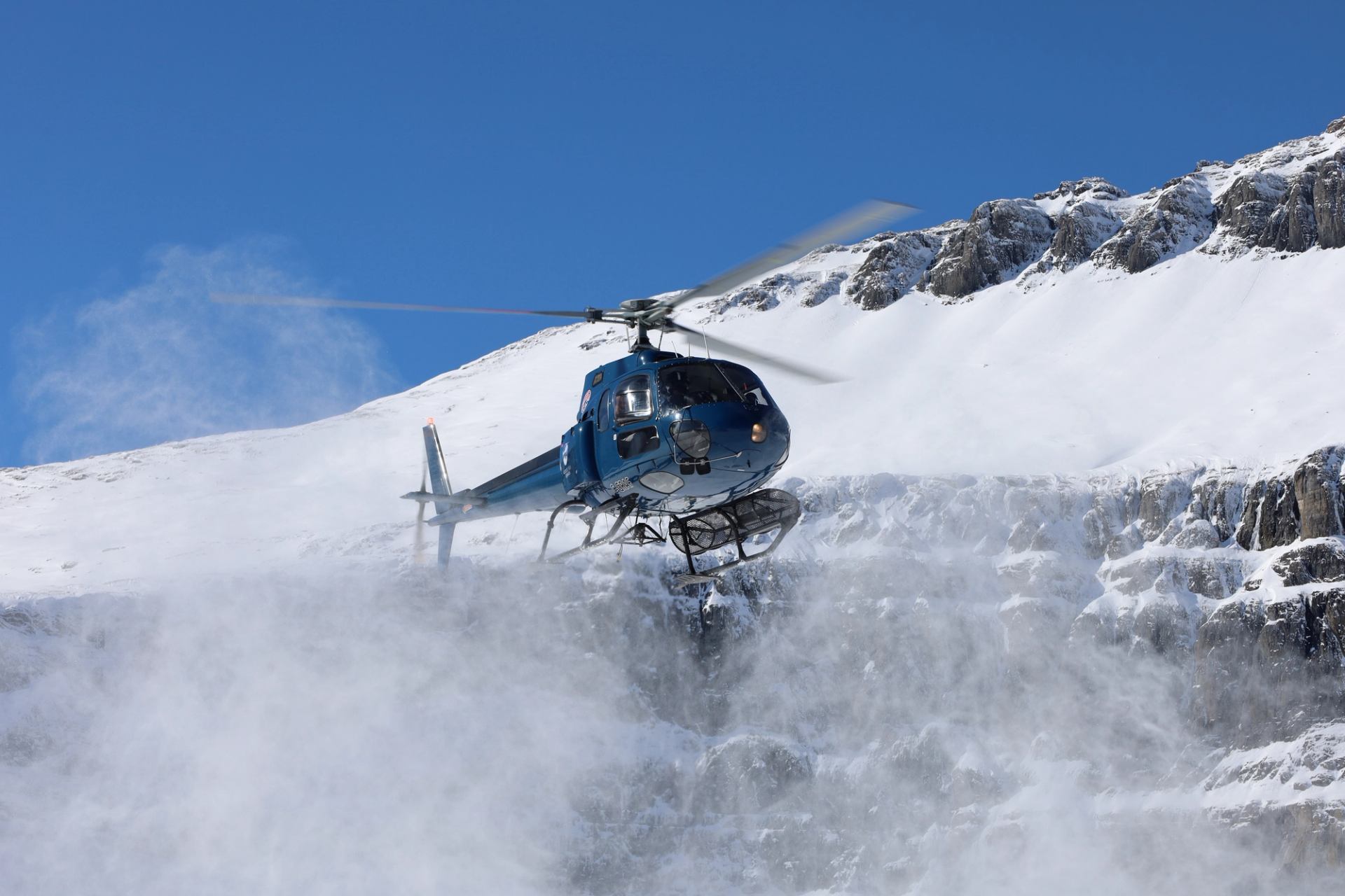 Helicopter flying low over a snow covered glacier in the Canadian Rockies.