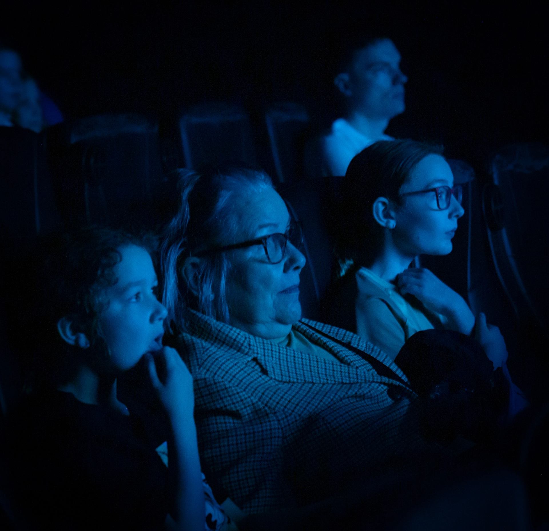 Three people watching a film in the theatre. 