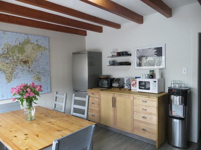 Cozy kitchen with wood table, pink flowers, world map, and modern appliances.