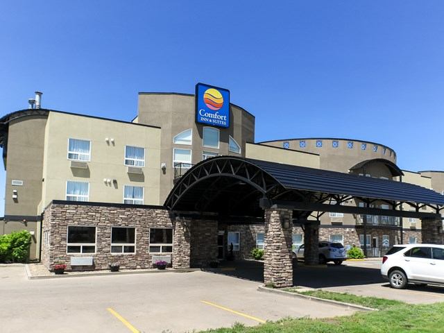 Comfort Inn & Suites hotel exterior with stone arch entry and parked cars.