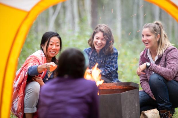 People gathered around a fire pit, camping at Wood Buffalo National Park.