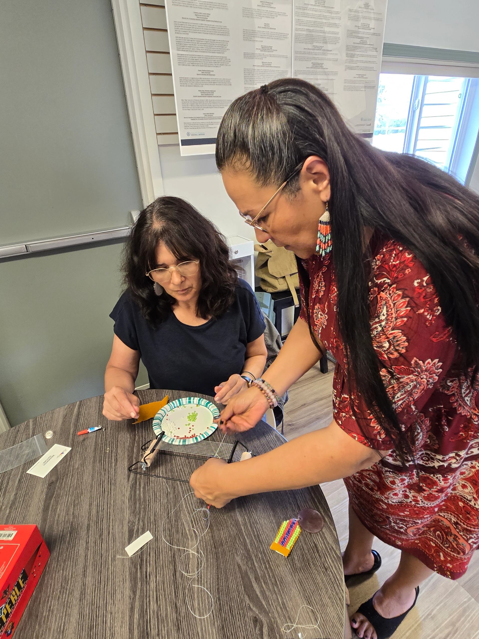 Being instructed on  how to bead using a loom
