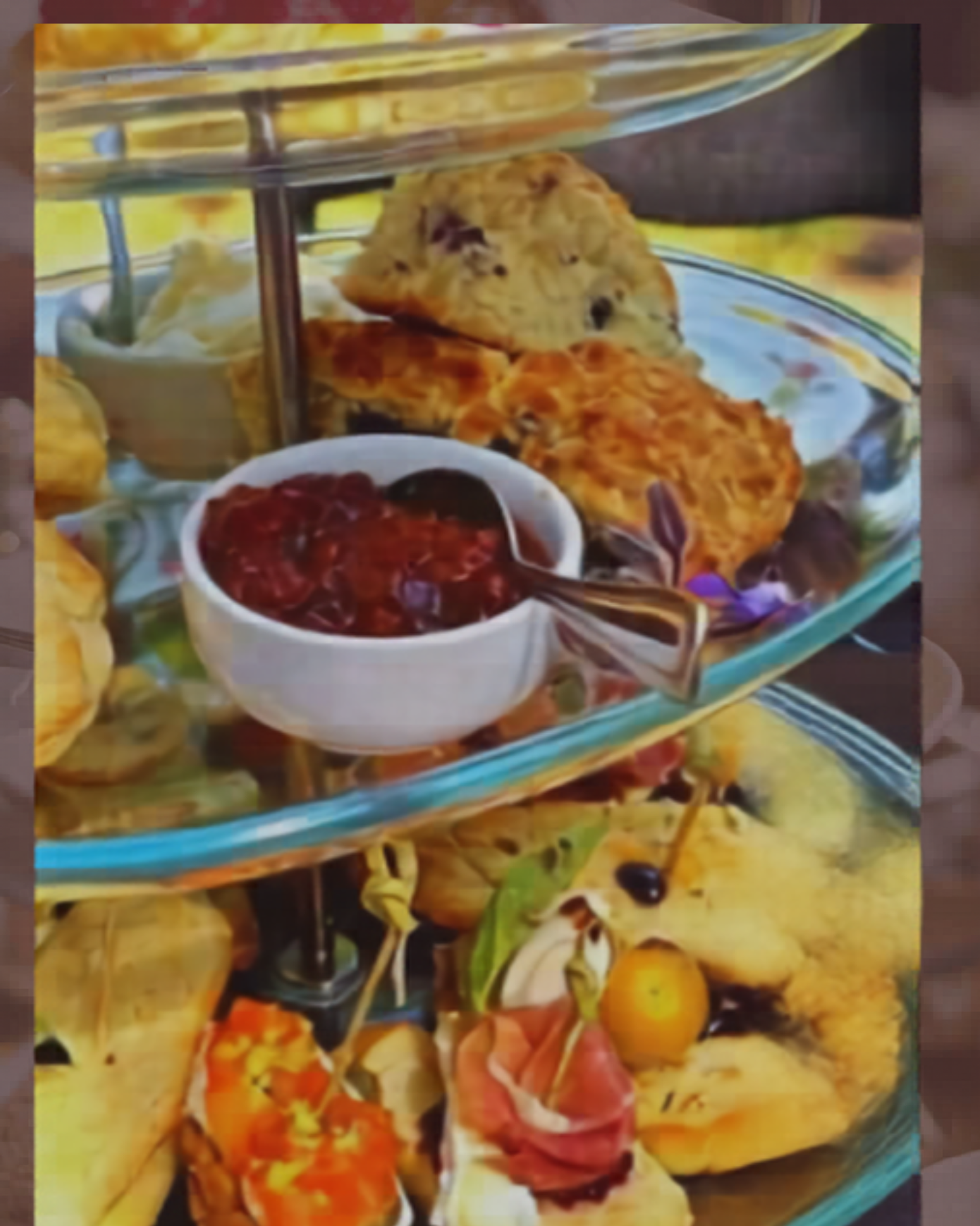 Tiered glass stand with scones, jam, cream and assorted savoury appetizers.