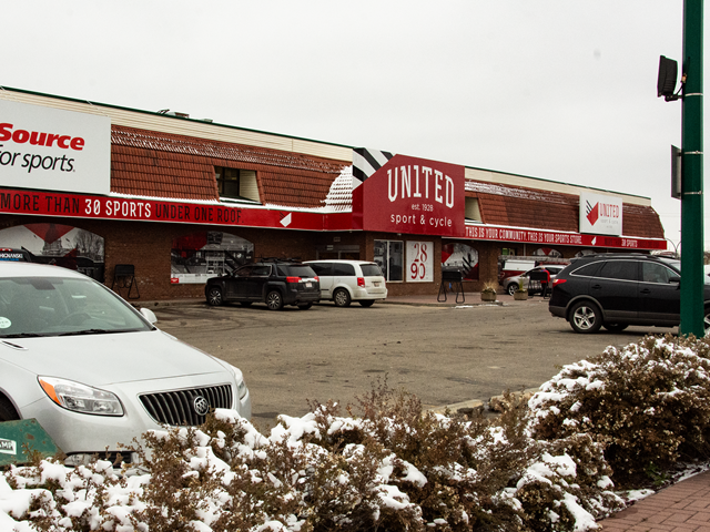 Sporting goods store exterior with signage for United Sport & Cycle and parked vehicles.