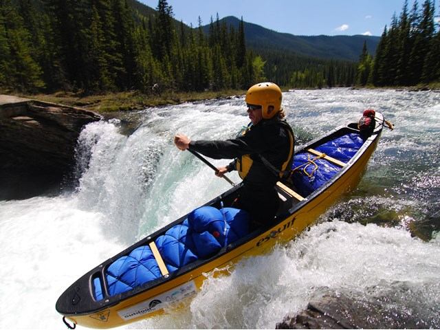 A person kayaking down a waterfall in Sheep River.