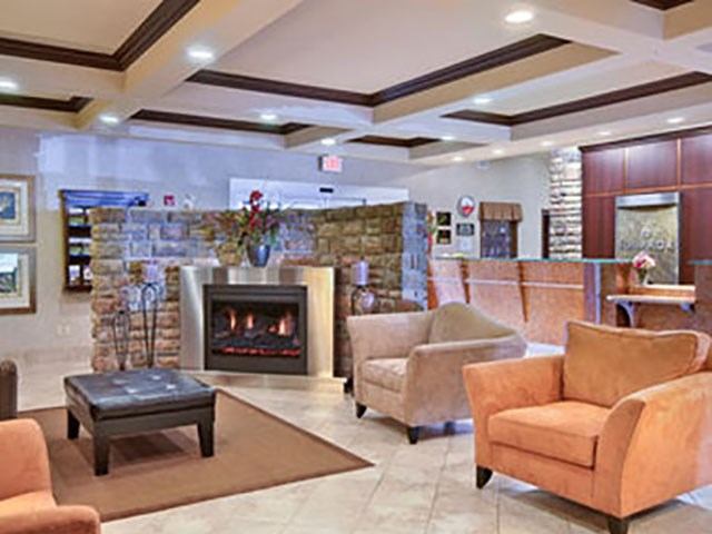Hotel lobby with modern seating, coffee table, and a fireplace near the reception desk.