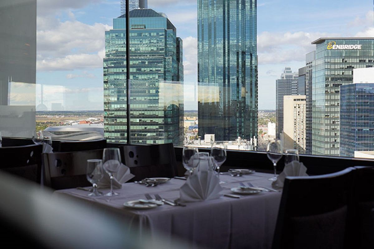 Restaurant table setting with stemmed glasses and downtown Calgary skyscrapers in view.