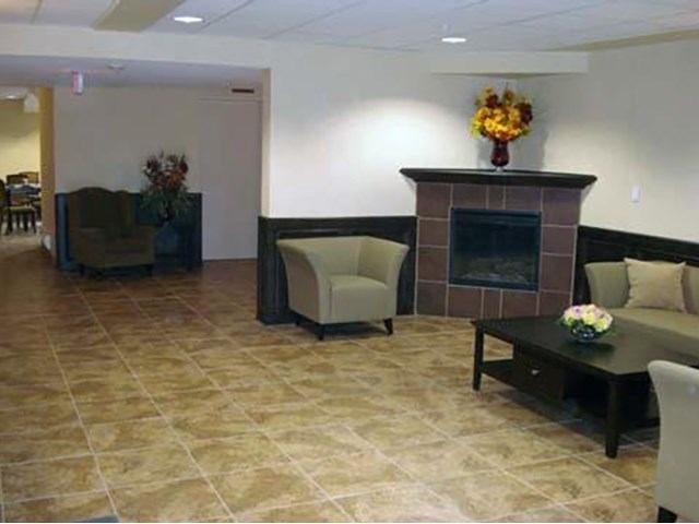 Hotel lobby with tiled floor, seating, and a reception counter with floral arrangement.