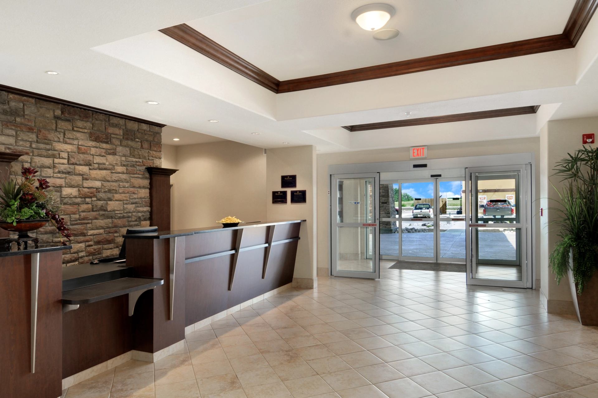 Hotel lobby reception desk with stone accent wall and glass entrance doors.