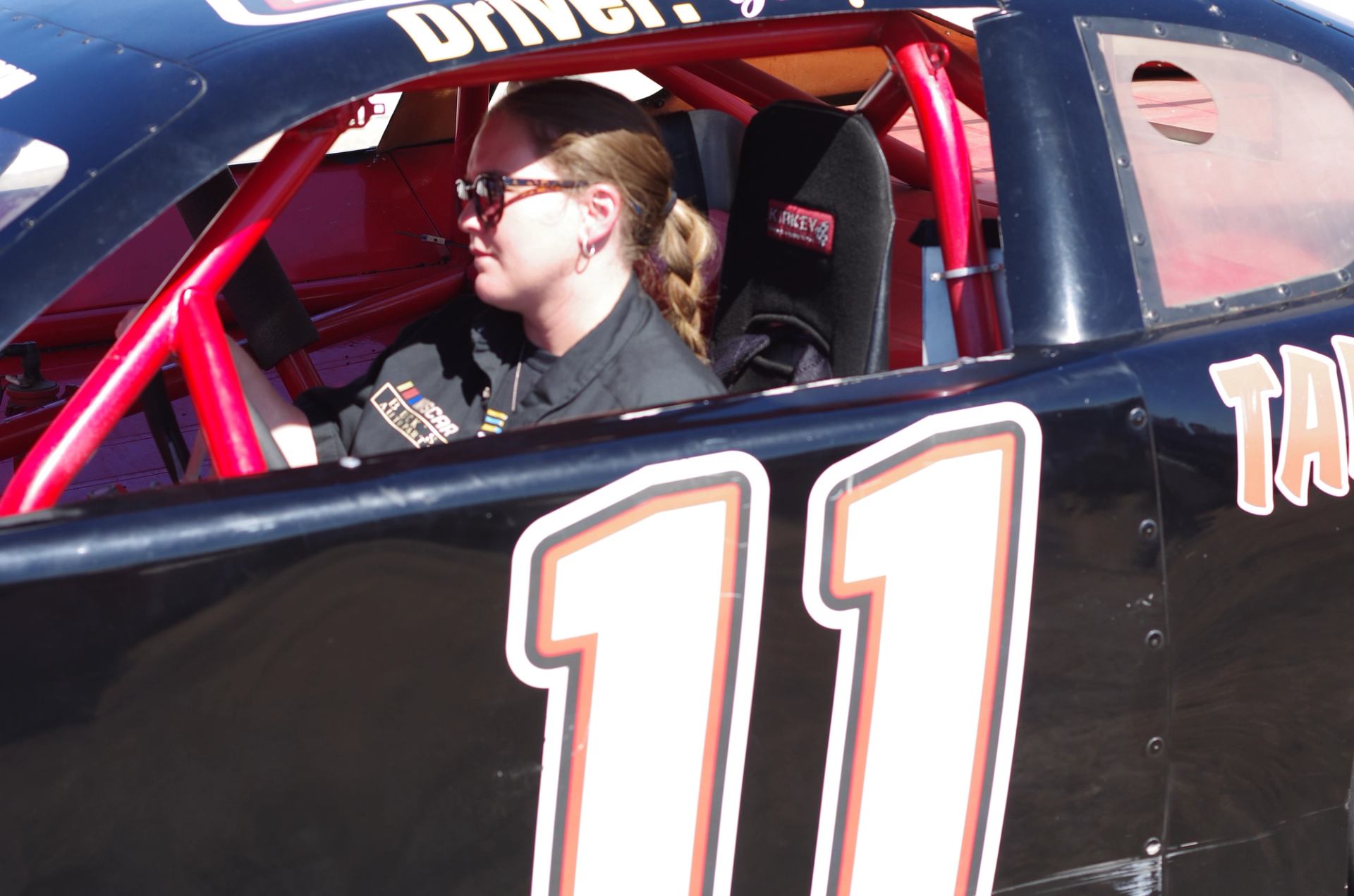 Person seated inside a NASCAR stock car with number 11 visible on the door.