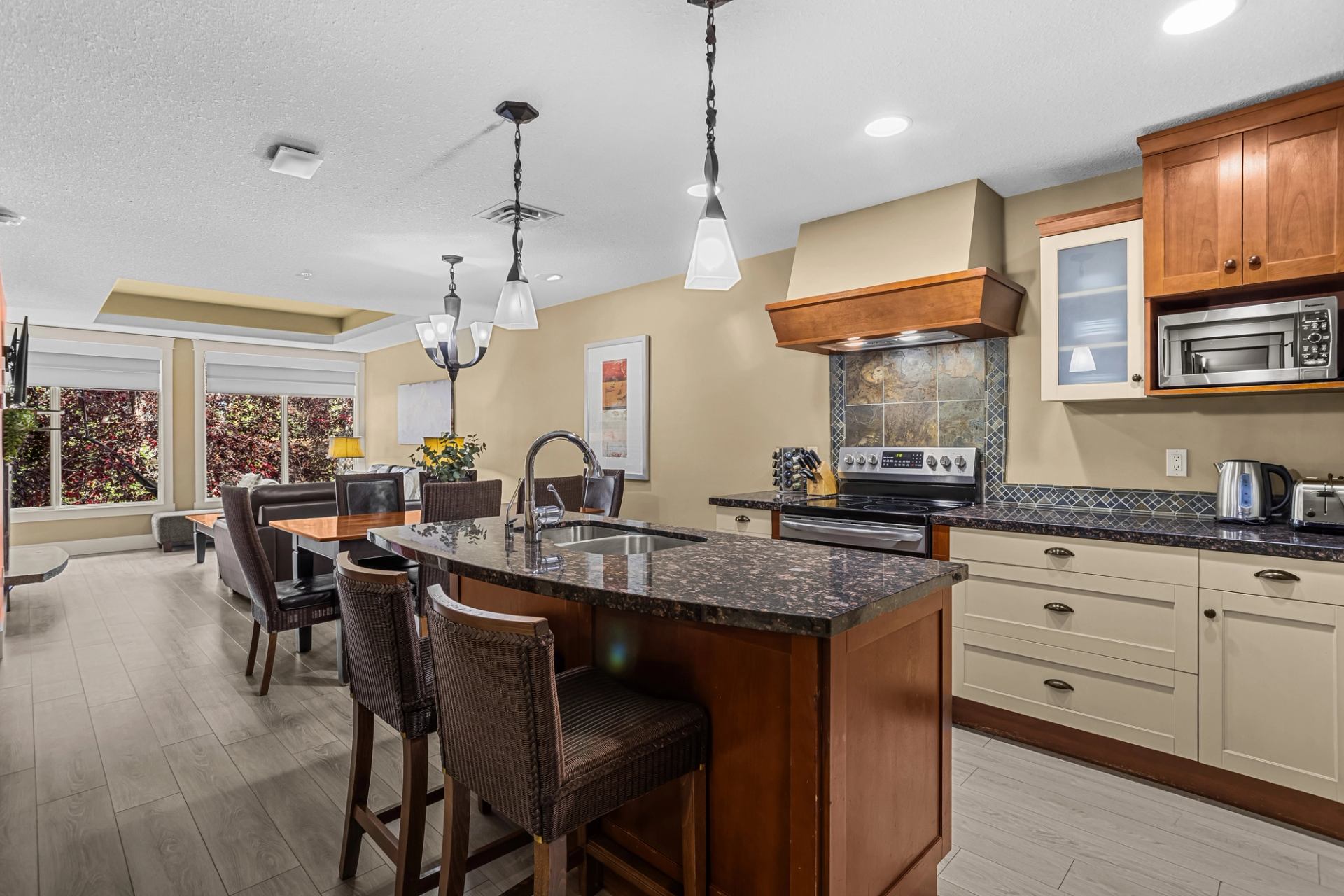 Open kitchen and dining area with granite island, wicker stools and wood cabinetry.