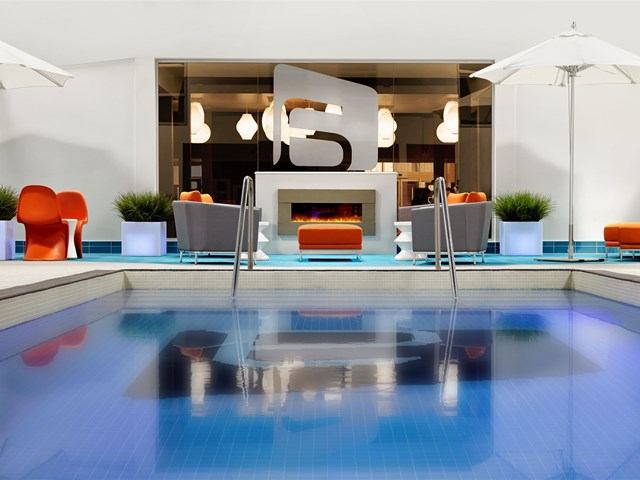 Outdoor pool with lounge seating, umbrellas, and modern decor at Aloft Calgary University.