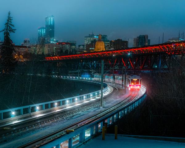 A light rail train moves along a curved track in the evening.