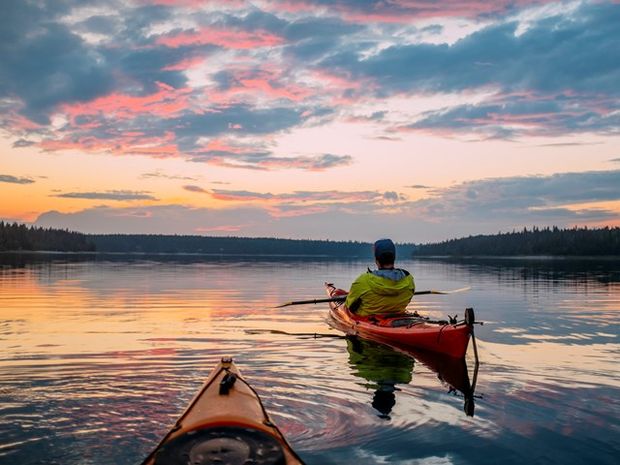 People canoeing on a lake at sunset in Wood Buffalo National Park.