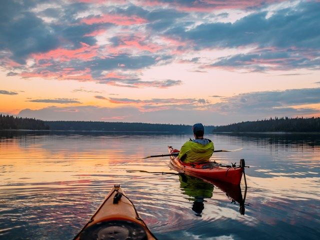 People canoeing on a lake at sunset in Wood Buffalo National Park.