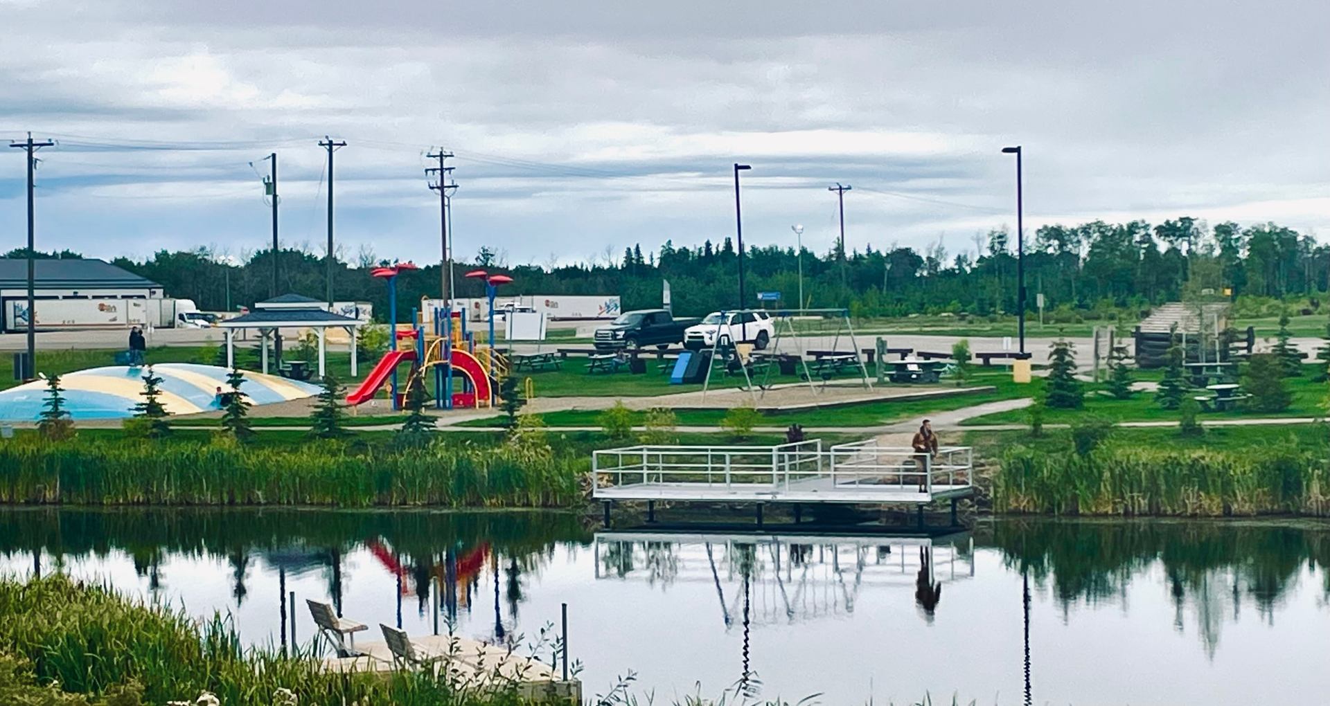Dock overlooking pond with playground and picnic area at Cecil Thompson Park campground