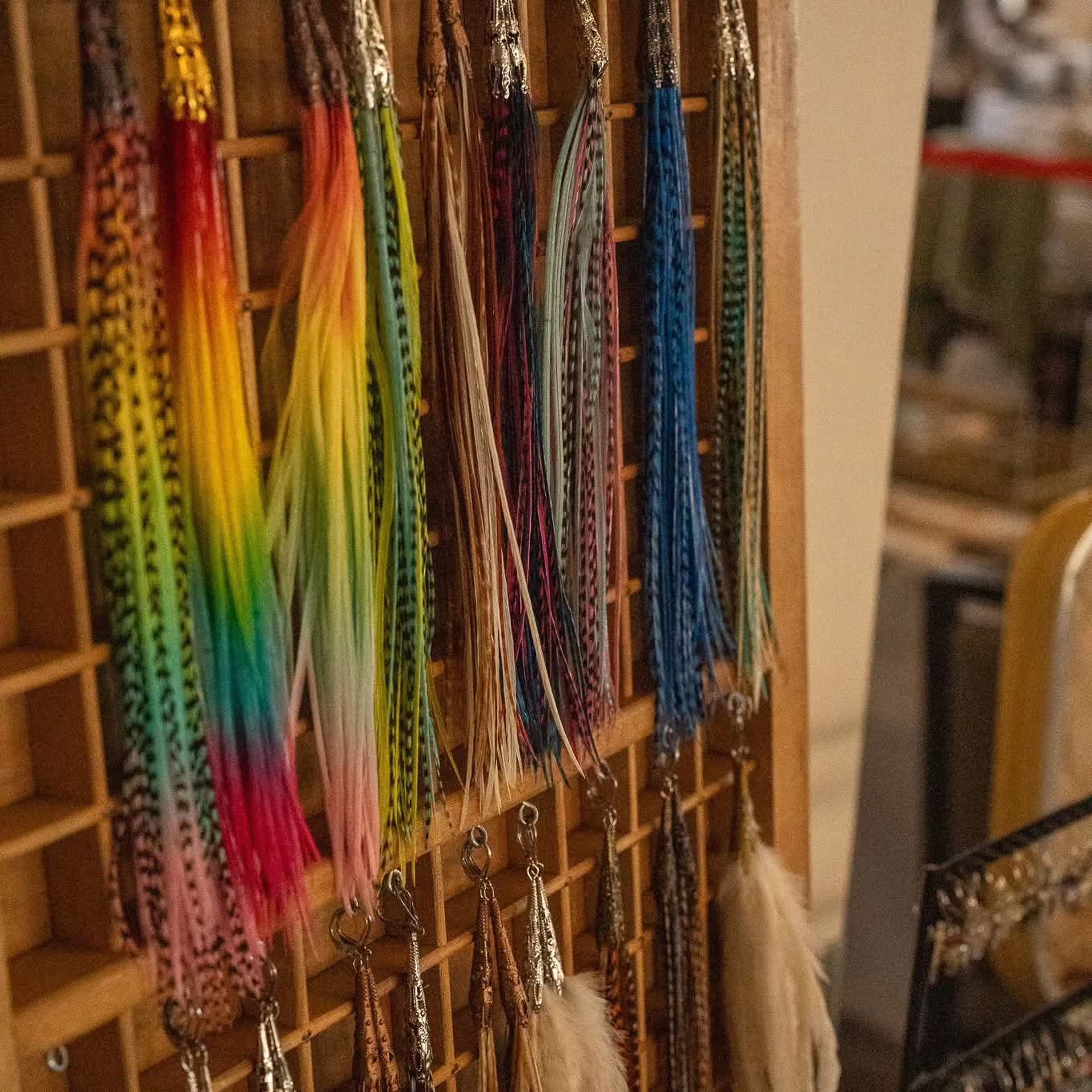 Colorful tassel keychains hang in rows on a wooden display grid.