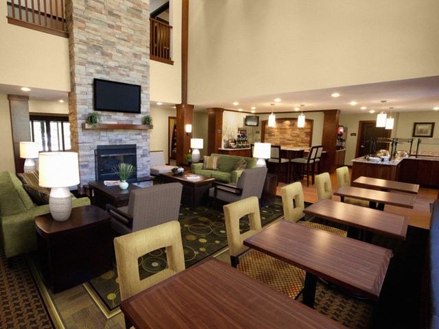Hotel lounge with tables, chairs, and stone fireplace near bar area