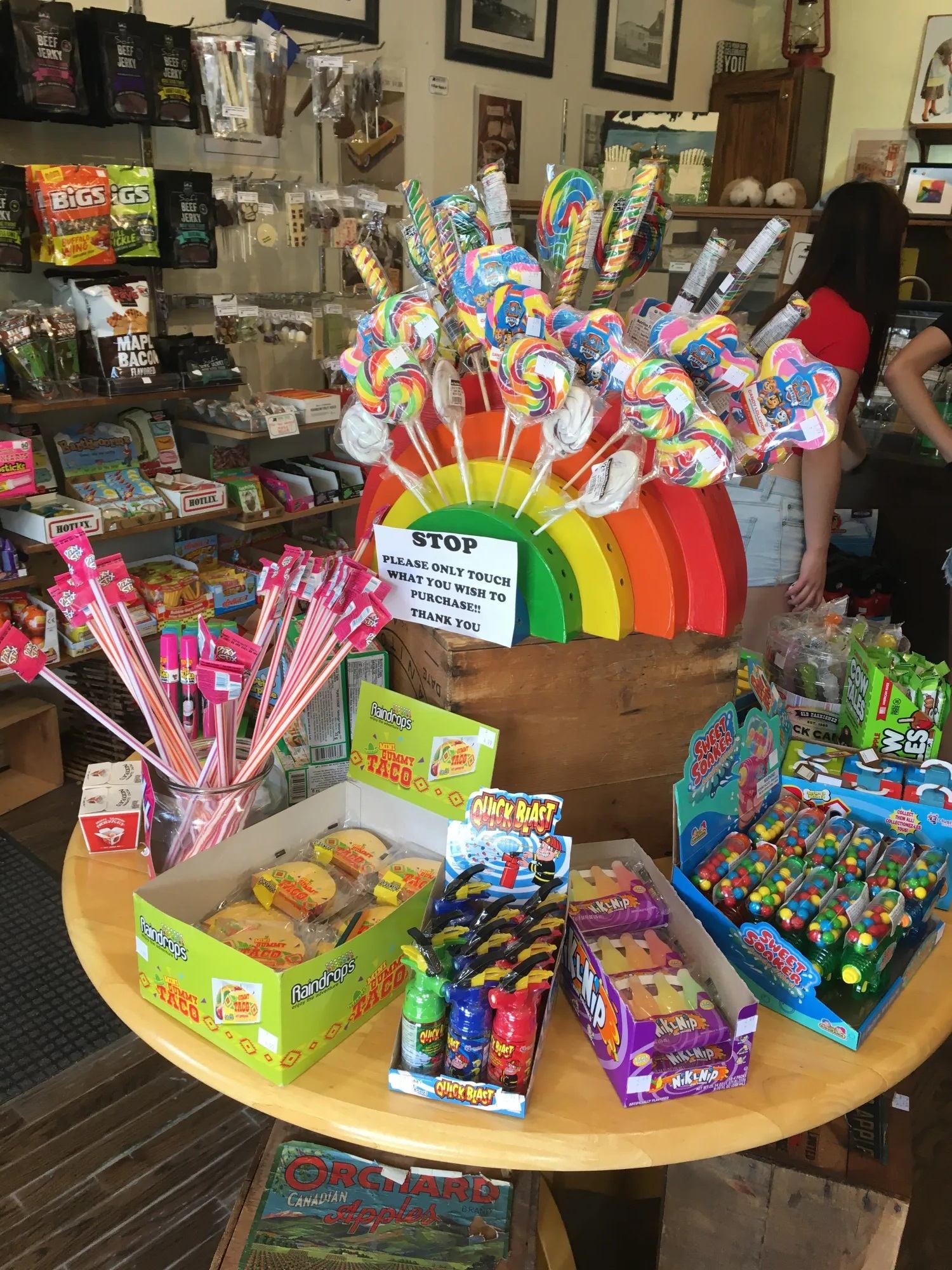 Candy display case with wrapped lollipops, gummies, and boxed snacks in a shop.