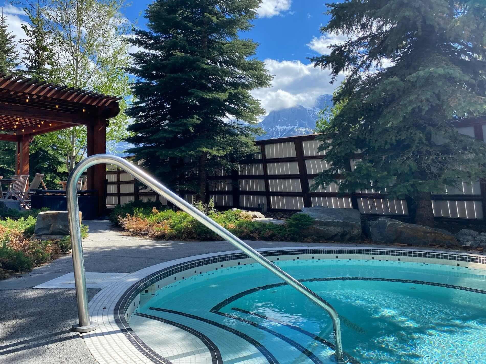 Outdoor hot tub with mountain views and tall pine trees.