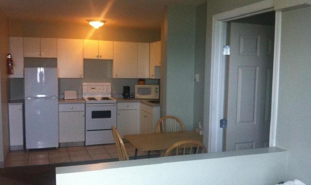 Kitchen area with white cabinets, appliances, and a small dining table.