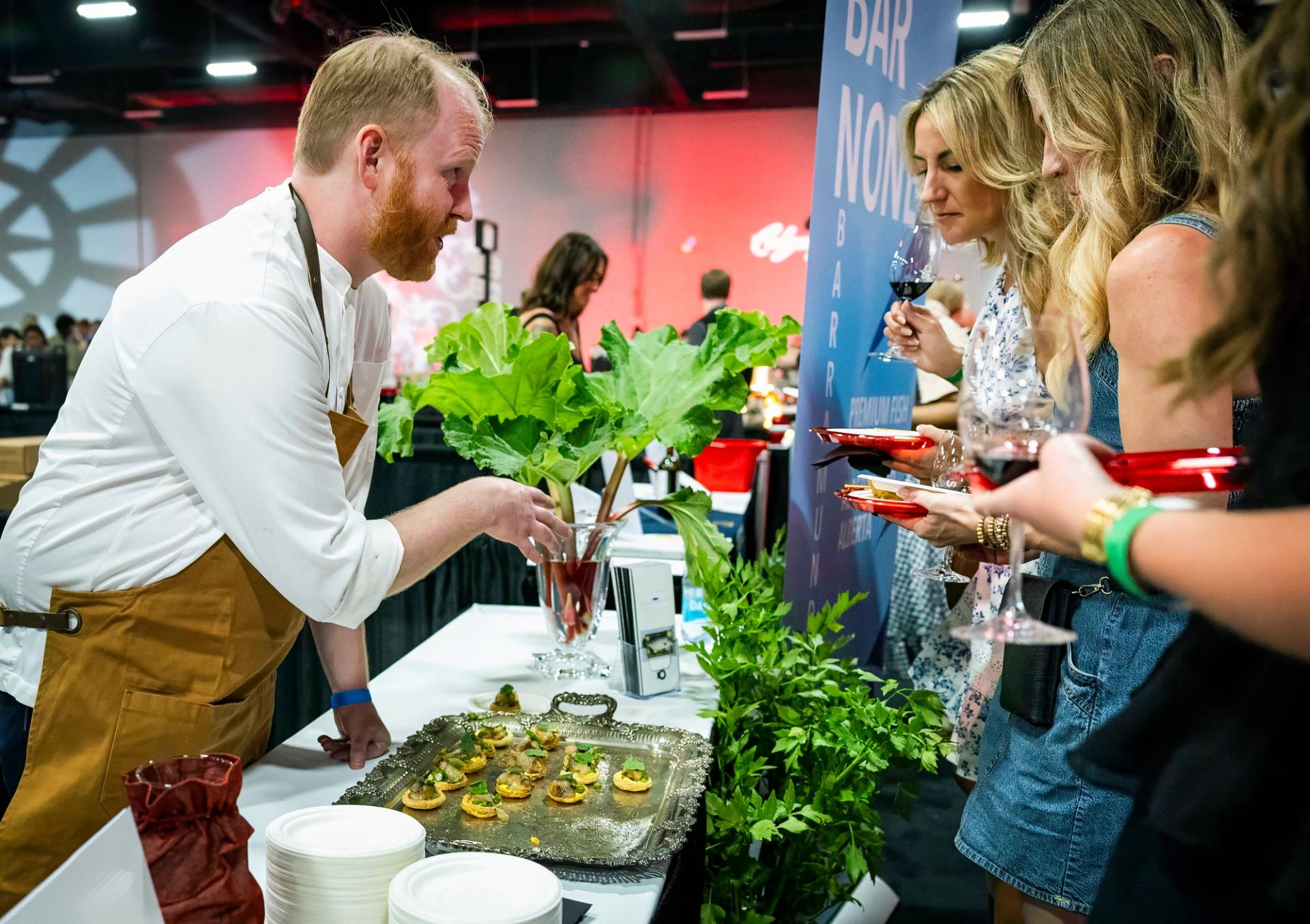 Chef presenting small gourmet dishes to guests at a tasting station