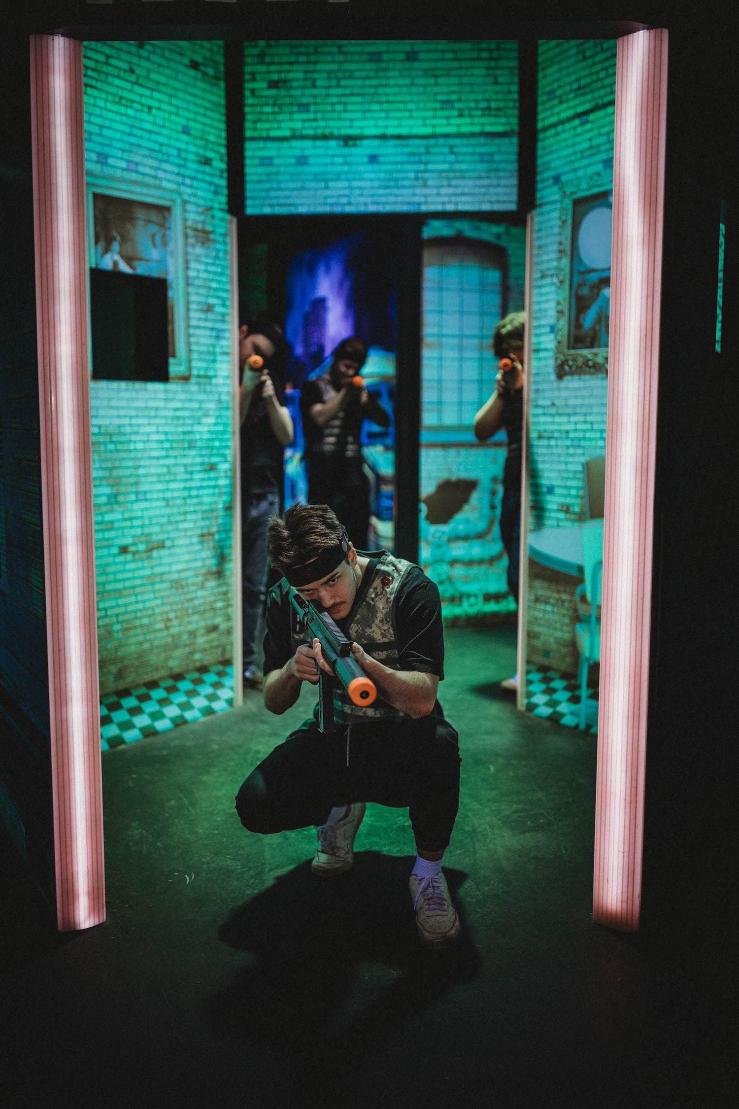 Arcade shooter game with a player aiming in a neon-lit hallway at The Alley YMM.