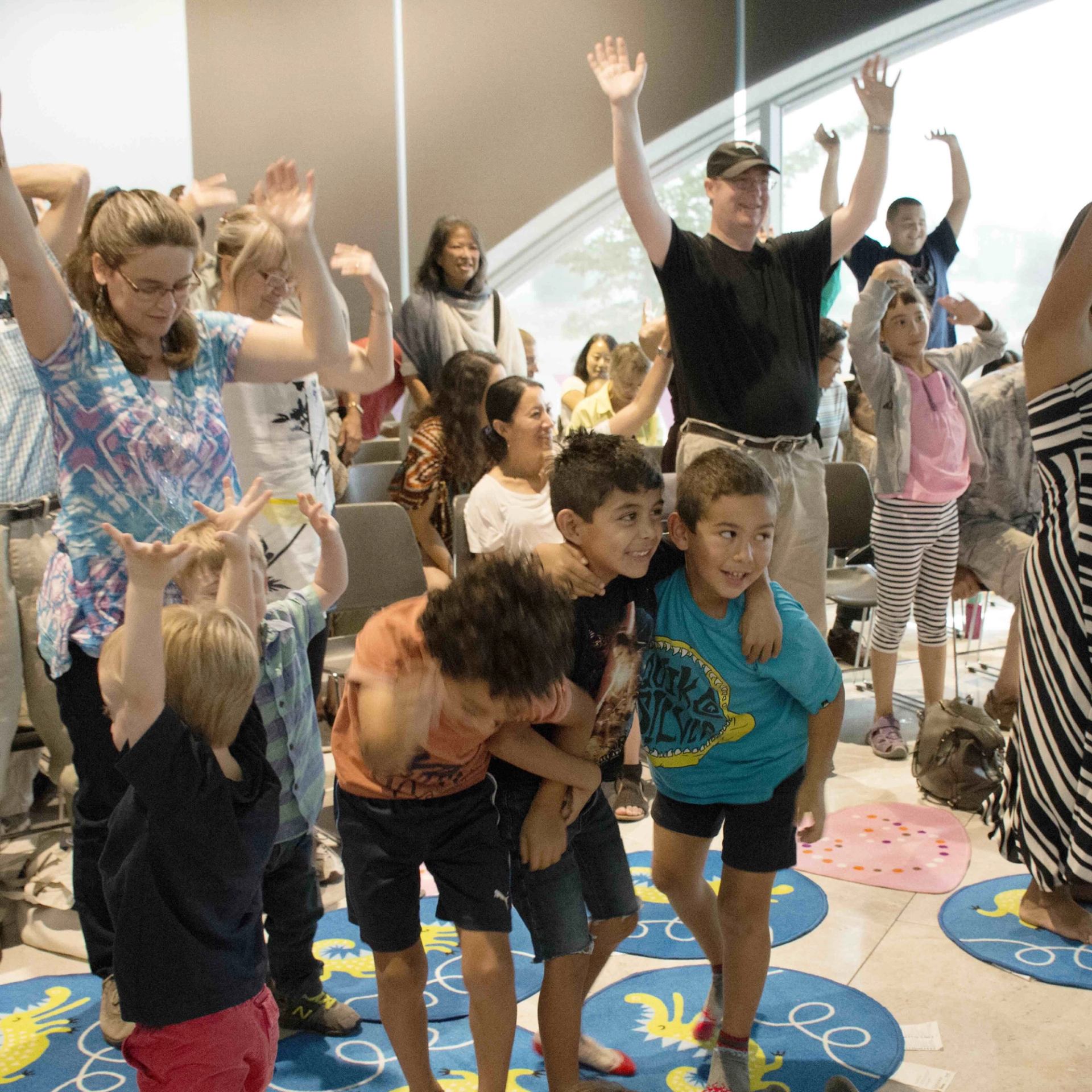 Children and adults engaged in a lively indoor group activity.