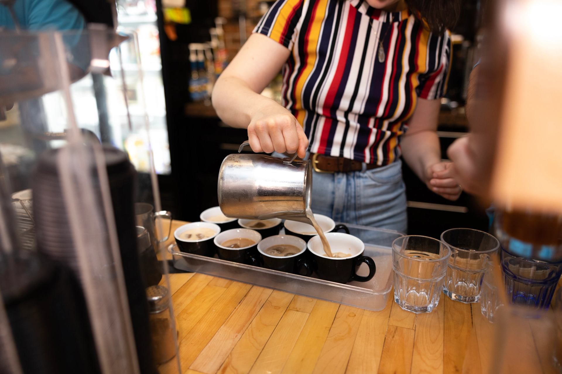 Barista pouring milk into coffee cups.