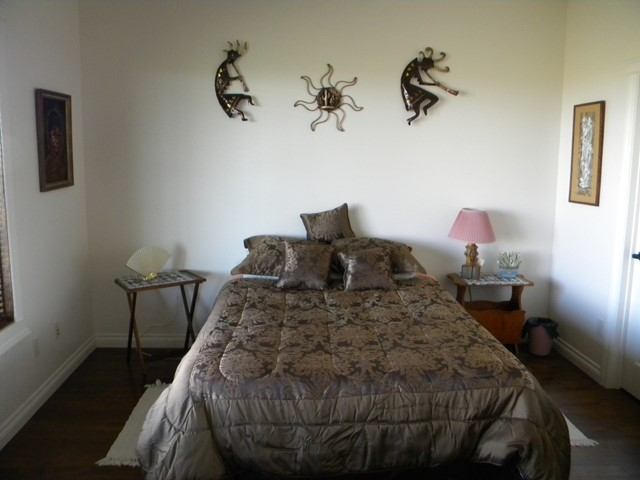 Bedroom with made bed, nightstands, table lamp, and three wall-mounted metal animal decorations.
