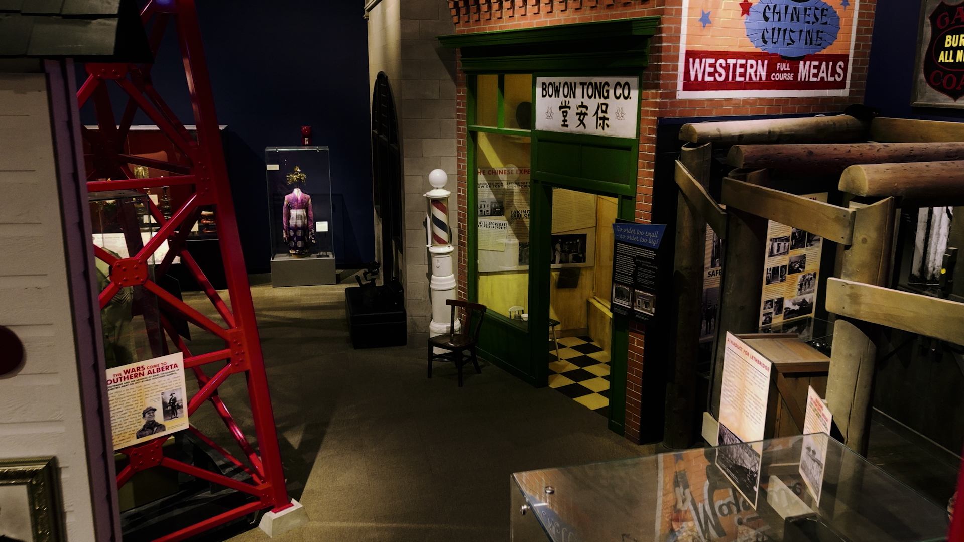 Indoor museum exhibit with historic storefronts, Chinese signage, barber pole and information panels.